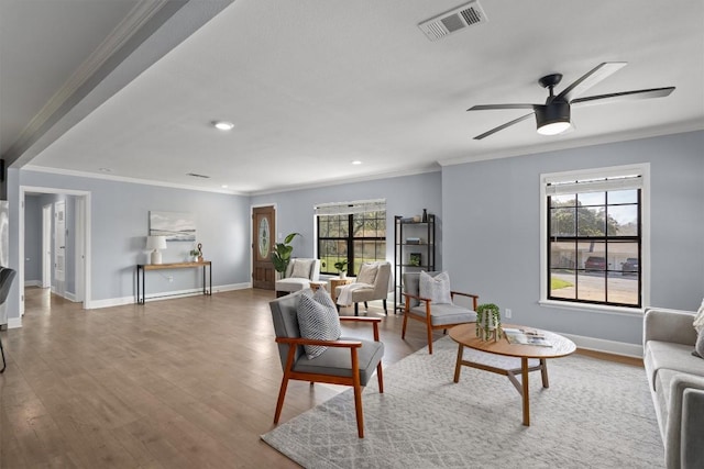 living room featuring ornamental molding, wood finished floors, visible vents, and baseboards