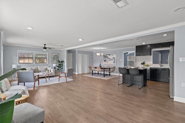 living room featuring ceiling fan, wood finished floors, recessed lighting, baseboards, and ornamental molding