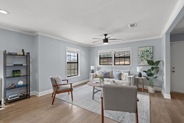 living room featuring crown molding, light wood-style flooring, baseboards, and a ceiling fan