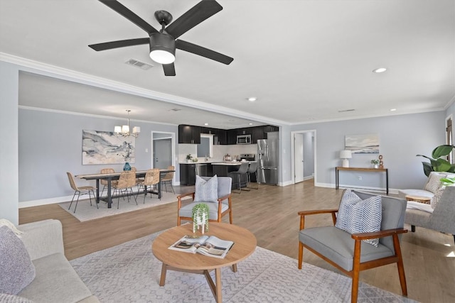 living area with crown molding, light wood-style floors, visible vents, and baseboards