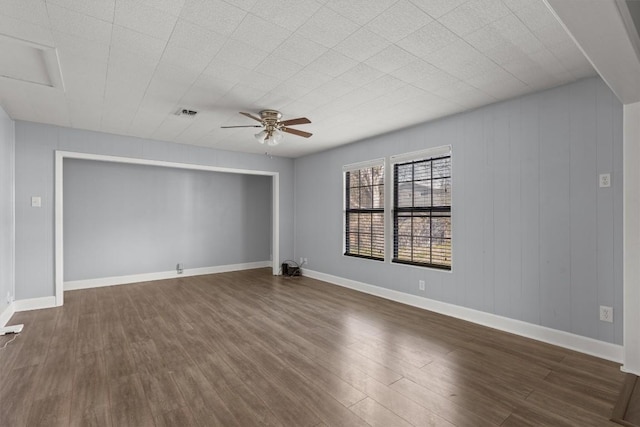 empty room with dark wood finished floors, baseboards, and a ceiling fan