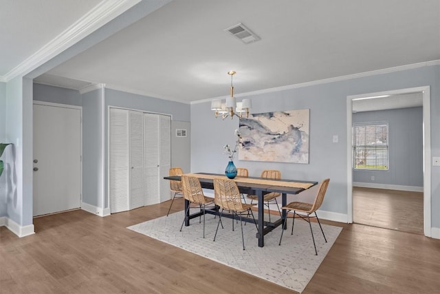 dining area featuring visible vents, wood finished floors, an inviting chandelier, crown molding, and baseboards