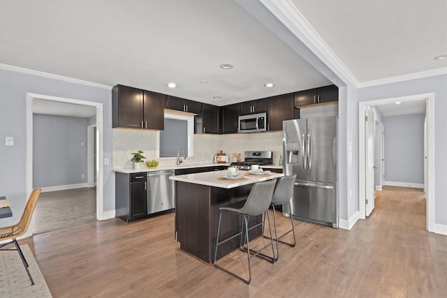 kitchen with light countertops, ornamental molding, light wood-type flooring, and stainless steel appliances