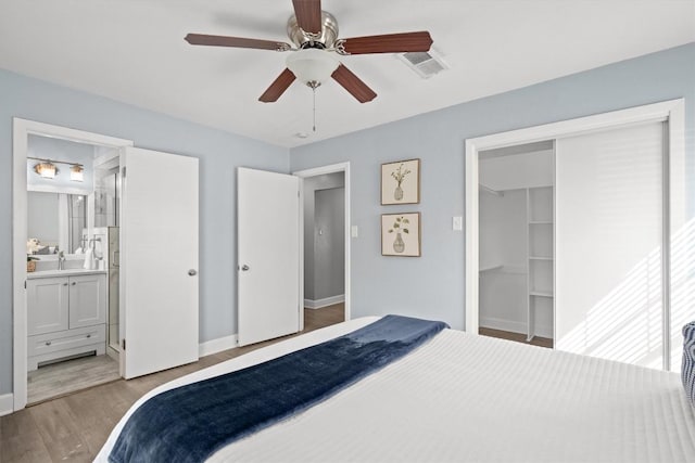 bedroom featuring light wood finished floors, visible vents, ensuite bathroom, a closet, and a sink