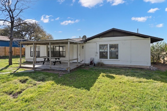 rear view of house featuring a lawn, a patio, and fence