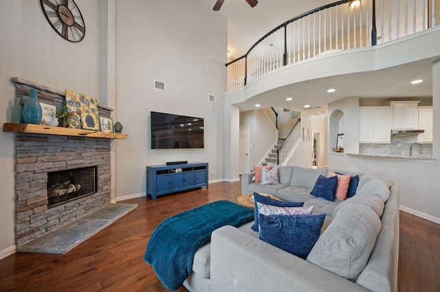 living area with a stone fireplace, stairway, wood finished floors, and baseboards