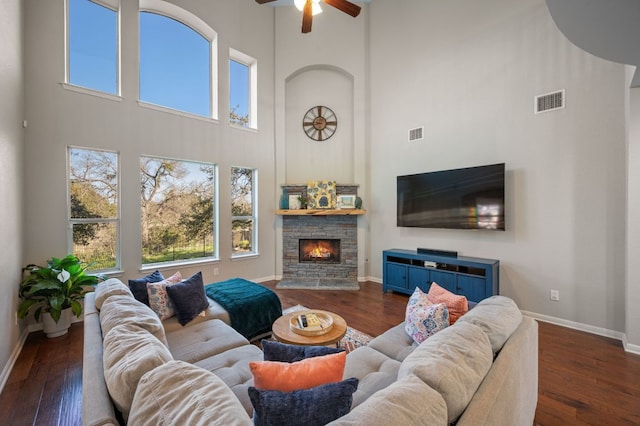 living area featuring a stone fireplace, visible vents, and hardwood / wood-style flooring