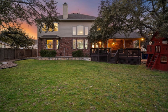 rear view of property featuring a yard, a wooden deck, a fenced backyard, and a chimney