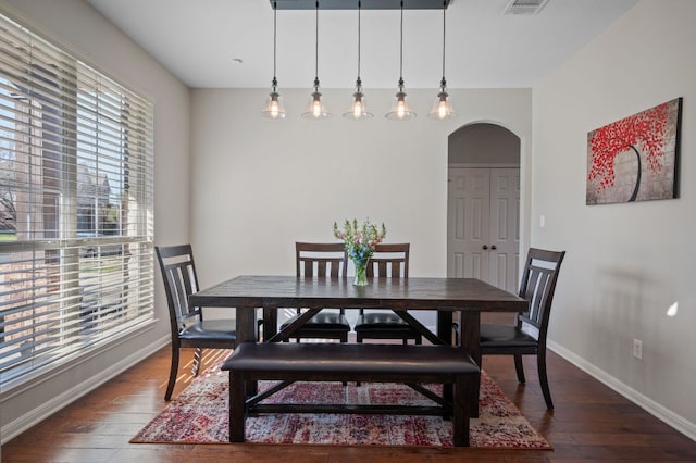 dining room with arched walkways, visible vents, baseboards, and hardwood / wood-style floors