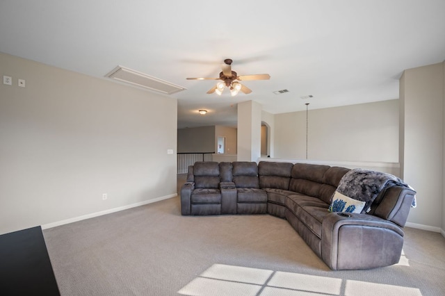 carpeted living room with visible vents, baseboards, attic access, and ceiling fan