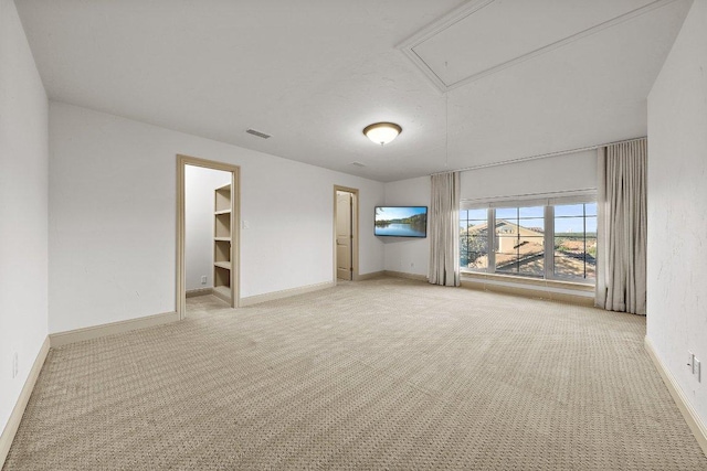 unfurnished room featuring light colored carpet, attic access, visible vents, and baseboards