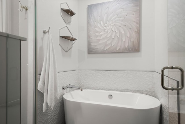 bathroom with tile walls and a freestanding tub