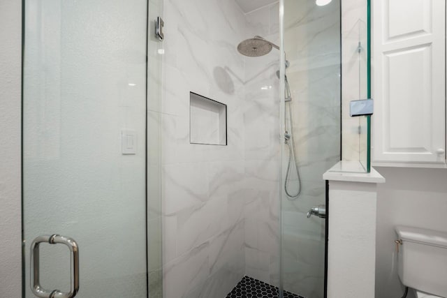 bathroom with a marble finish shower and toilet