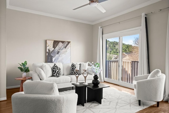 living room featuring crown molding, wood finished floors, baseboards, and ceiling fan