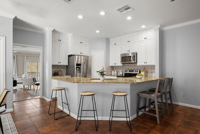 kitchen with light stone counters, stainless steel appliances, visible vents, and a peninsula