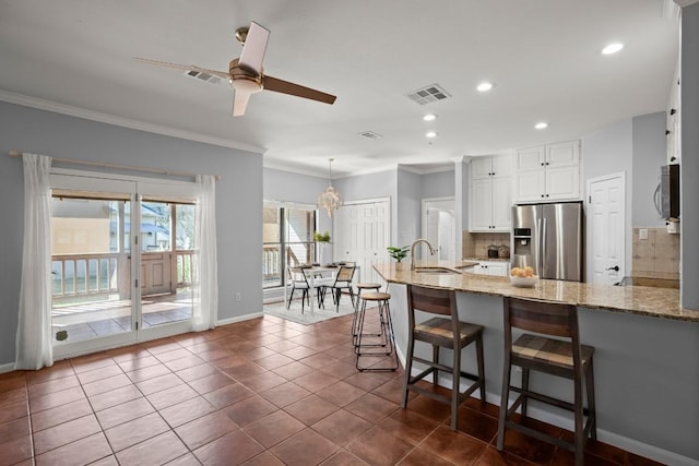 kitchen featuring visible vents, backsplash, light stone counters, appliances with stainless steel finishes, and a sink