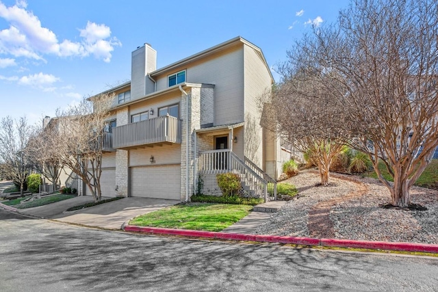 view of front of property featuring a garage, a balcony, concrete driveway, and a chimney