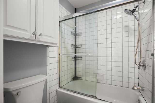 bathroom with toilet and bath / shower combo with glass door