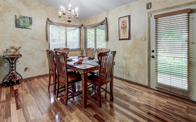 dining area with baseboards, an inviting chandelier, and wood finished floors