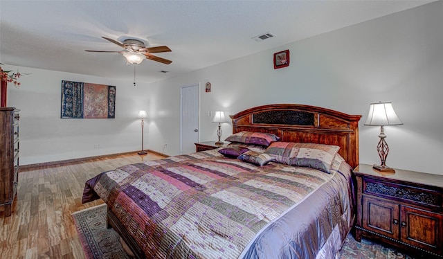 bedroom with visible vents, baseboards, ceiling fan, and wood finished floors