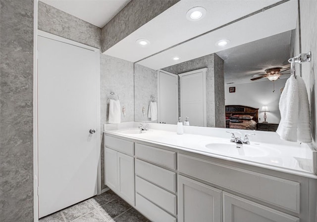 ensuite bathroom with double vanity, ensuite bath, ceiling fan, and a sink