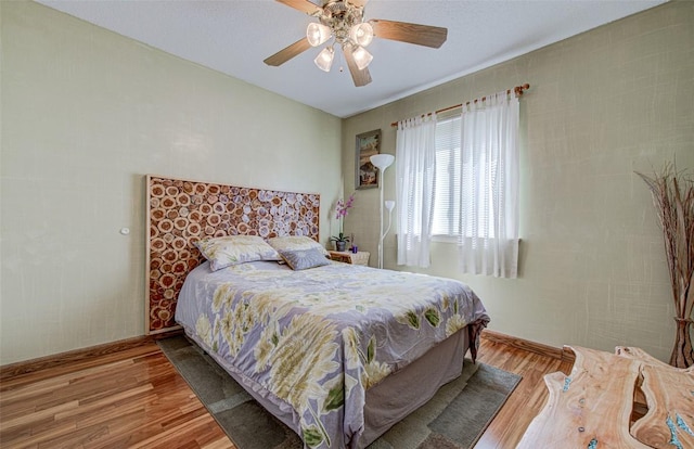 bedroom featuring baseboards, light wood finished floors, and ceiling fan