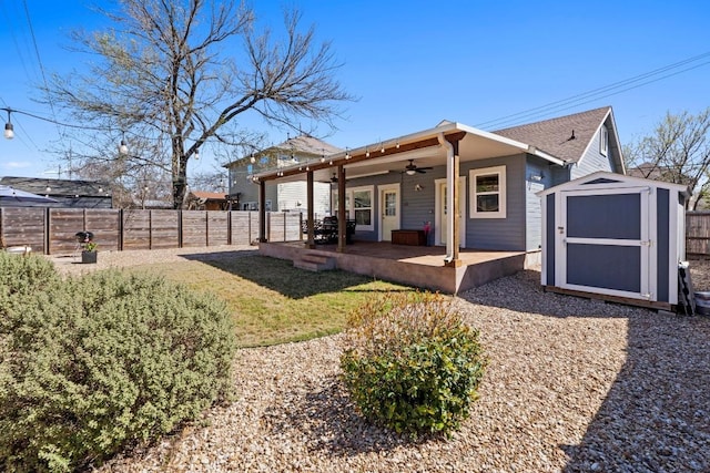 back of property with ceiling fan, a storage shed, a fenced backyard, an outdoor structure, and a patio area