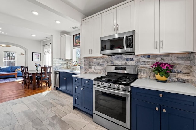 kitchen with appliances with stainless steel finishes, light countertops, blue cabinets, and a sink