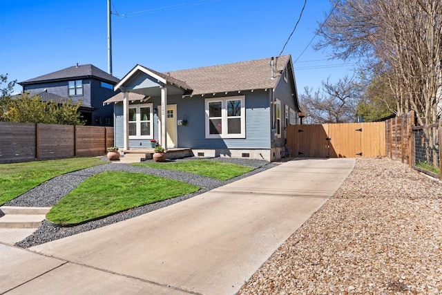 bungalow with a shingled roof, fence, a front lawn, and a gate