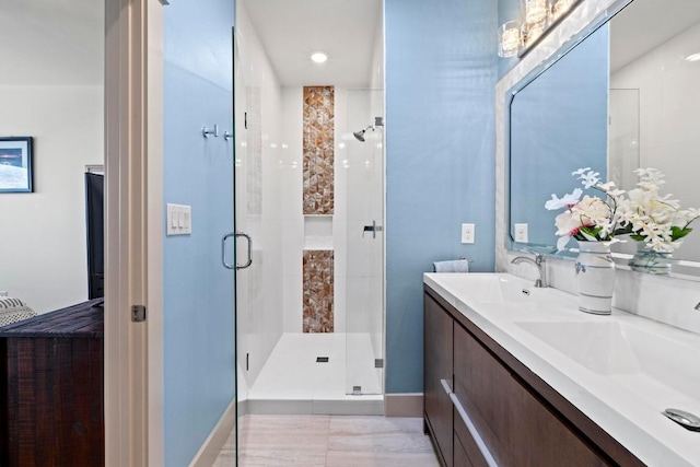 bathroom featuring a sink, a stall shower, and double vanity