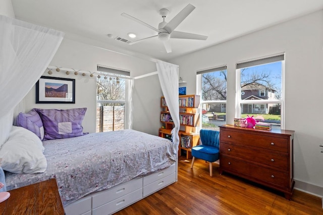 bedroom featuring ceiling fan, visible vents, multiple windows, and wood finished floors