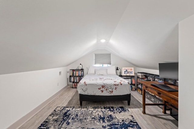 bedroom with vaulted ceiling, light wood-style floors, and baseboards