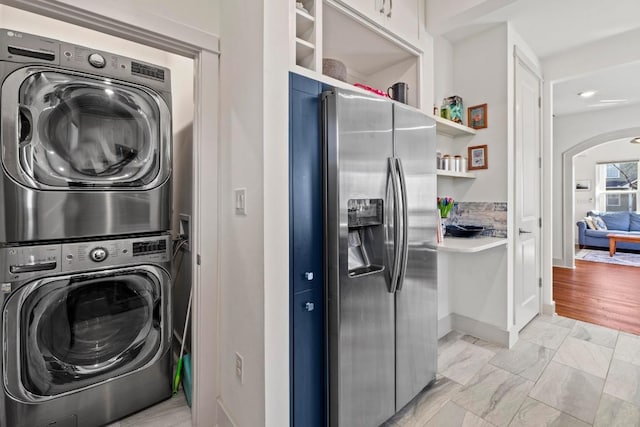 clothes washing area with laundry area, stacked washer and dryer, arched walkways, and marble finish floor