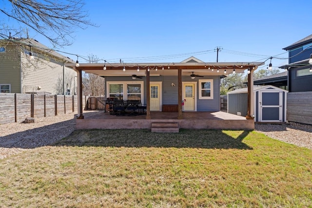 rear view of property with a storage unit, an outbuilding, a fenced backyard, and a patio area