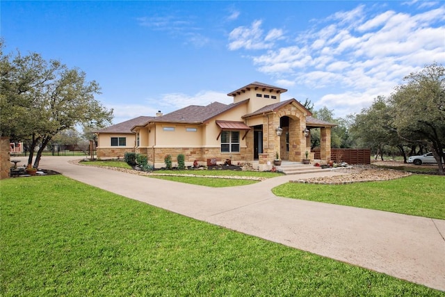 mediterranean / spanish house with stucco siding, stone siding, and a front lawn