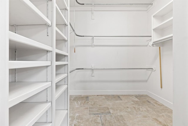 walk in closet featuring stone finish flooring