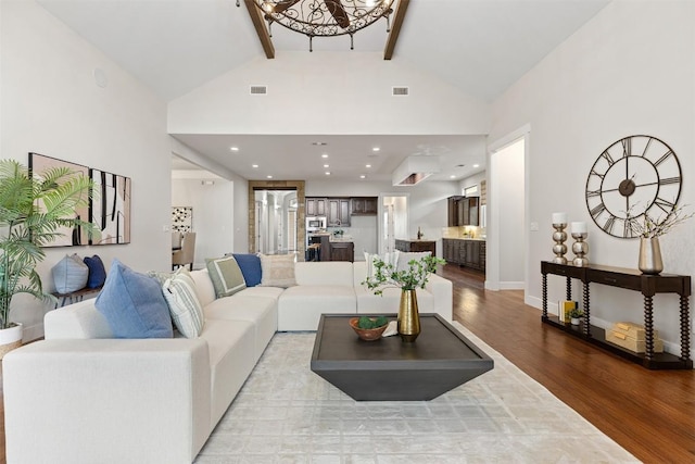 living area featuring wood finished floors, beamed ceiling, high vaulted ceiling, a chandelier, and baseboards
