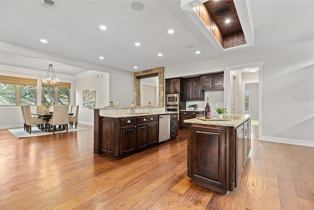 kitchen with dark brown cabinets, visible vents, appliances with stainless steel finishes, and a kitchen island with sink