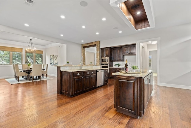 kitchen featuring an island with sink, baseboards, stainless steel appliances, dark brown cabinetry, and recessed lighting