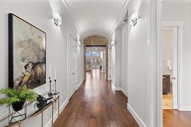 corridor featuring lofted ceiling, dark wood-type flooring, and baseboards