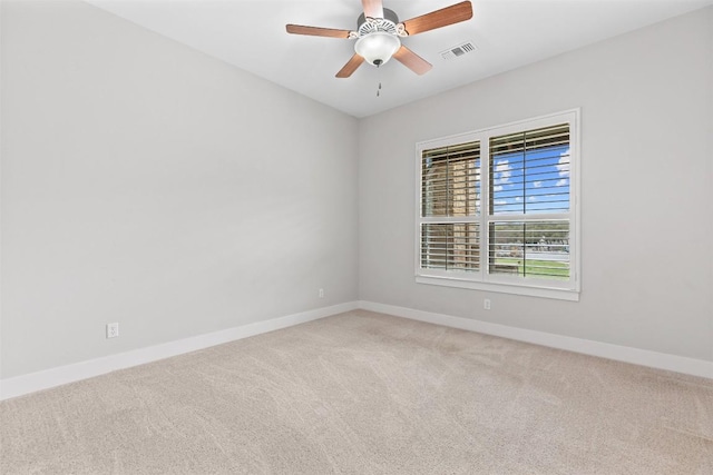 carpeted spare room with visible vents, a ceiling fan, and baseboards