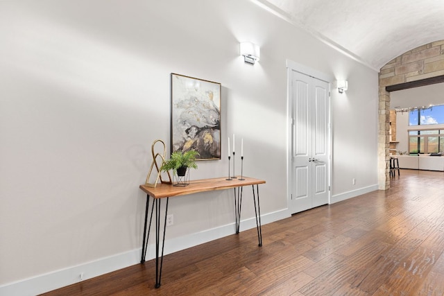 foyer entrance with wood finished floors, baseboards, and vaulted ceiling