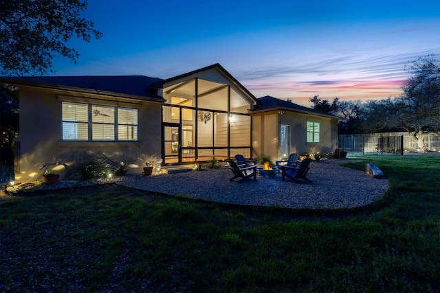back of property at dusk featuring a fire pit and stucco siding