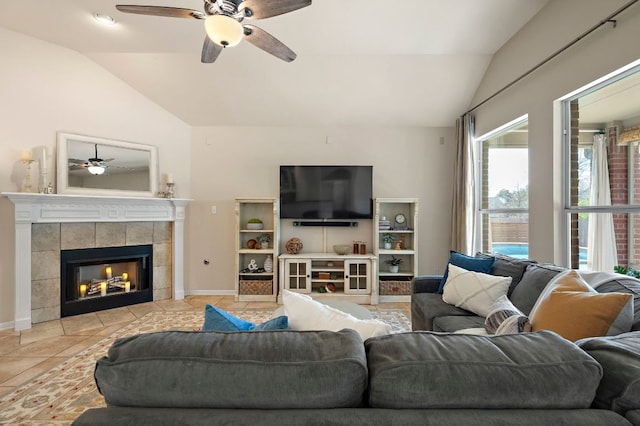 living area featuring vaulted ceiling, a ceiling fan, baseboards, and a tile fireplace