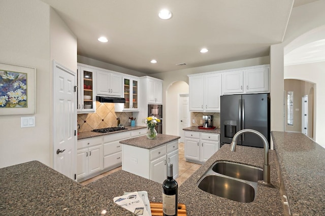 kitchen with arched walkways, gas cooktop, stainless steel refrigerator with ice dispenser, and a sink