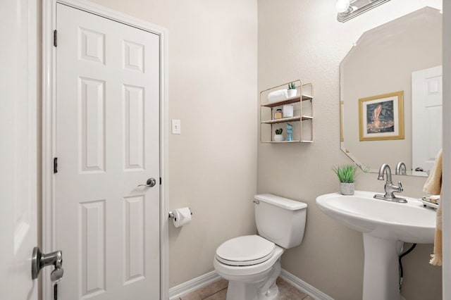 half bathroom with tile patterned floors, toilet, and baseboards