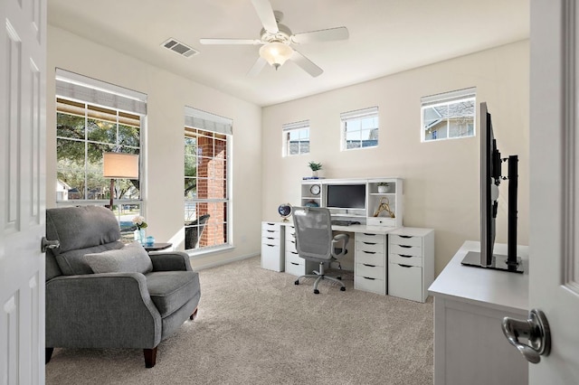 office area with light colored carpet, a healthy amount of sunlight, visible vents, and a ceiling fan