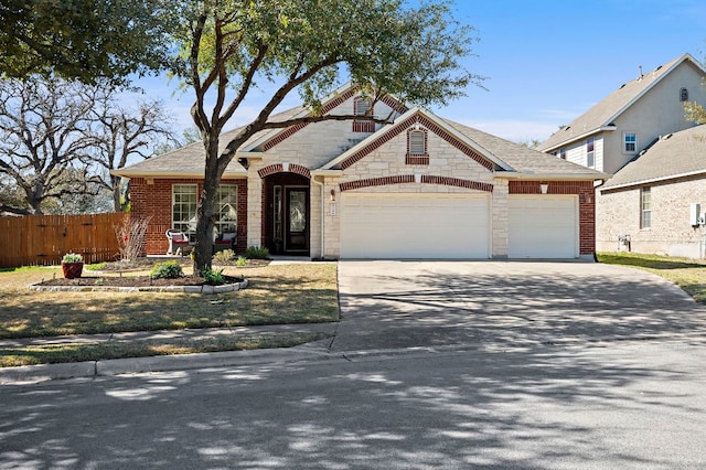 view of front of house with stone siding, concrete driveway, an attached garage, and fence