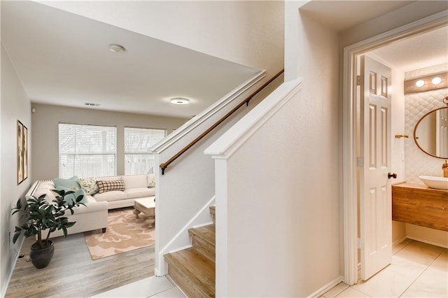 staircase featuring wood finished floors, baseboards, and visible vents