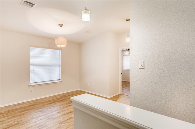 empty room with light wood-style flooring, baseboards, and visible vents